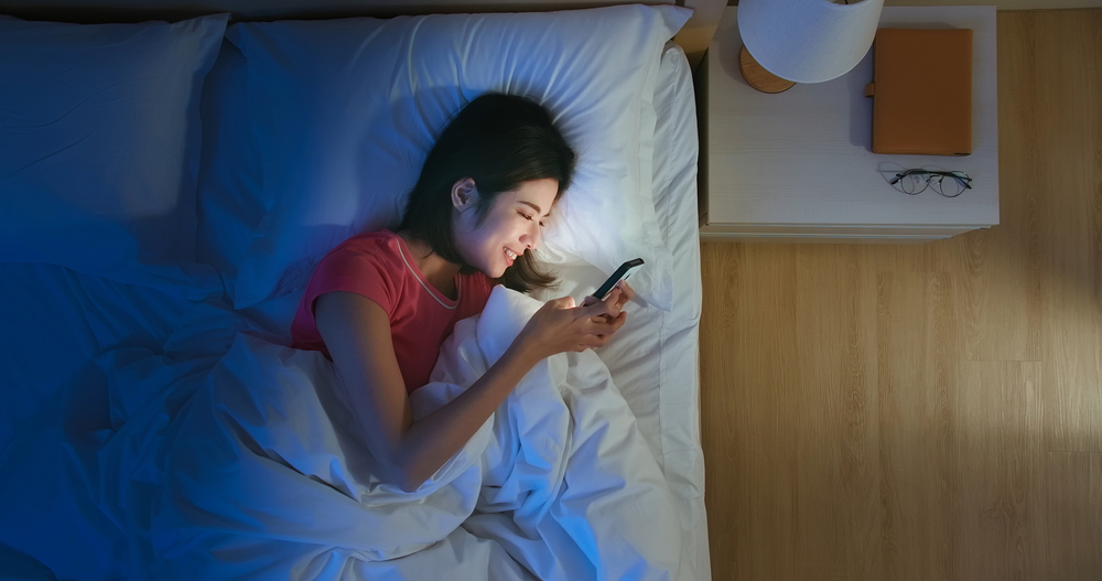 Overhead View of asian woman use smartphone on bed at night